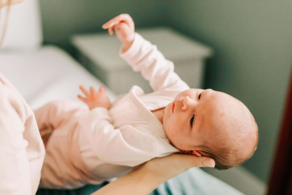 A one month old baby lays it's head on it's mother's hand