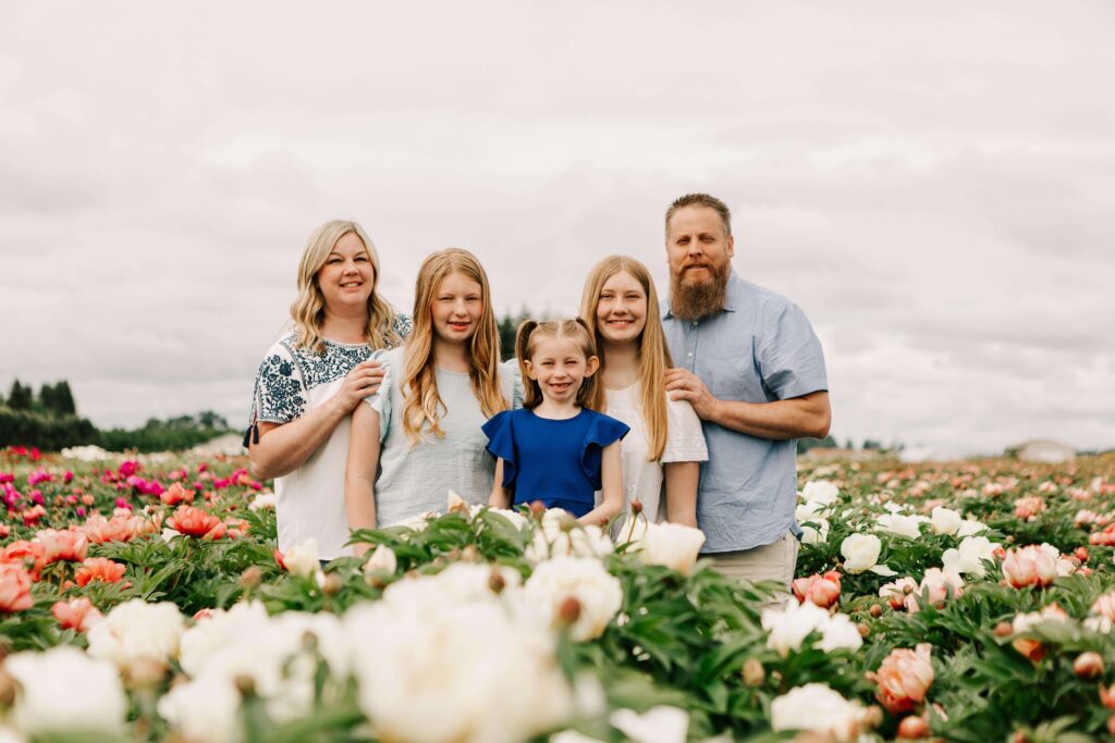 A family with mother, father, and three girls stands in the peonies at Adleman Peony Garden in Salem, OR