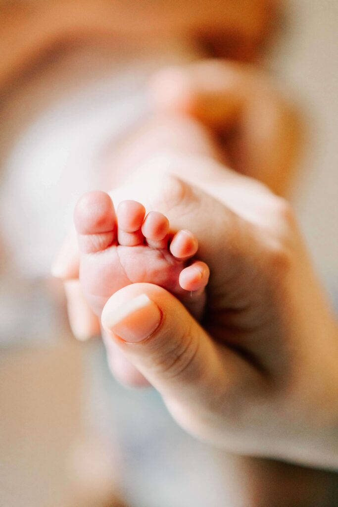 A mother holds her newborn's foot in her hand. Photo by Jen White Photgraphy Albany, OR