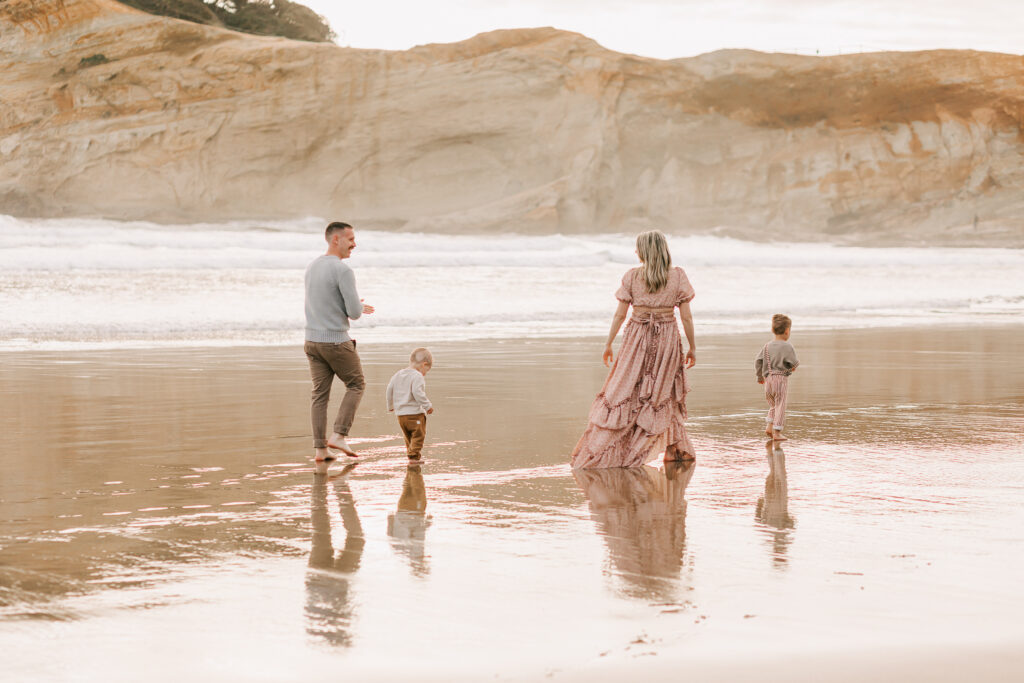 A family plays on the Oregon coast at Cape Kiwanda. They're posing for photos with Jen White Photography of Albany, OR