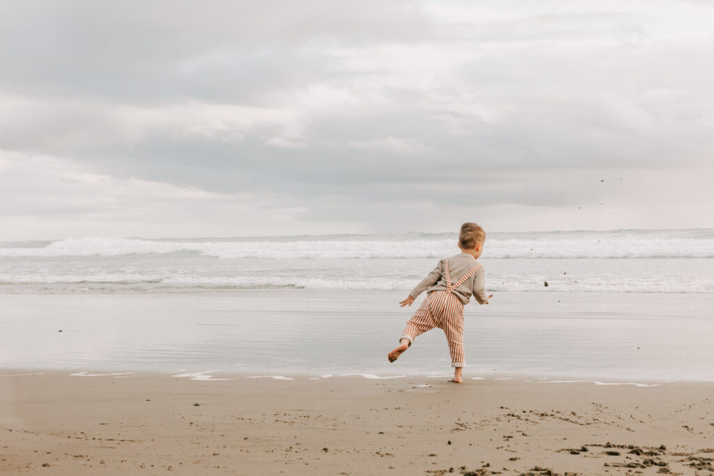 A small boy plays in the surf on the Oregon Coast during a family photo session