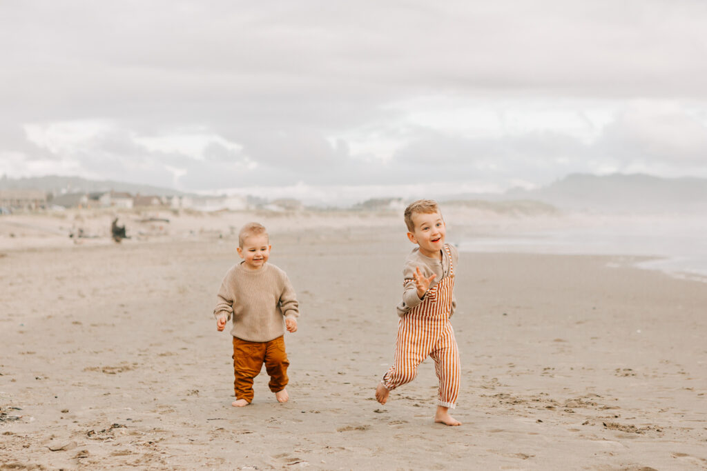 Two boys run in the sand at cape kiwanda state park, oregon