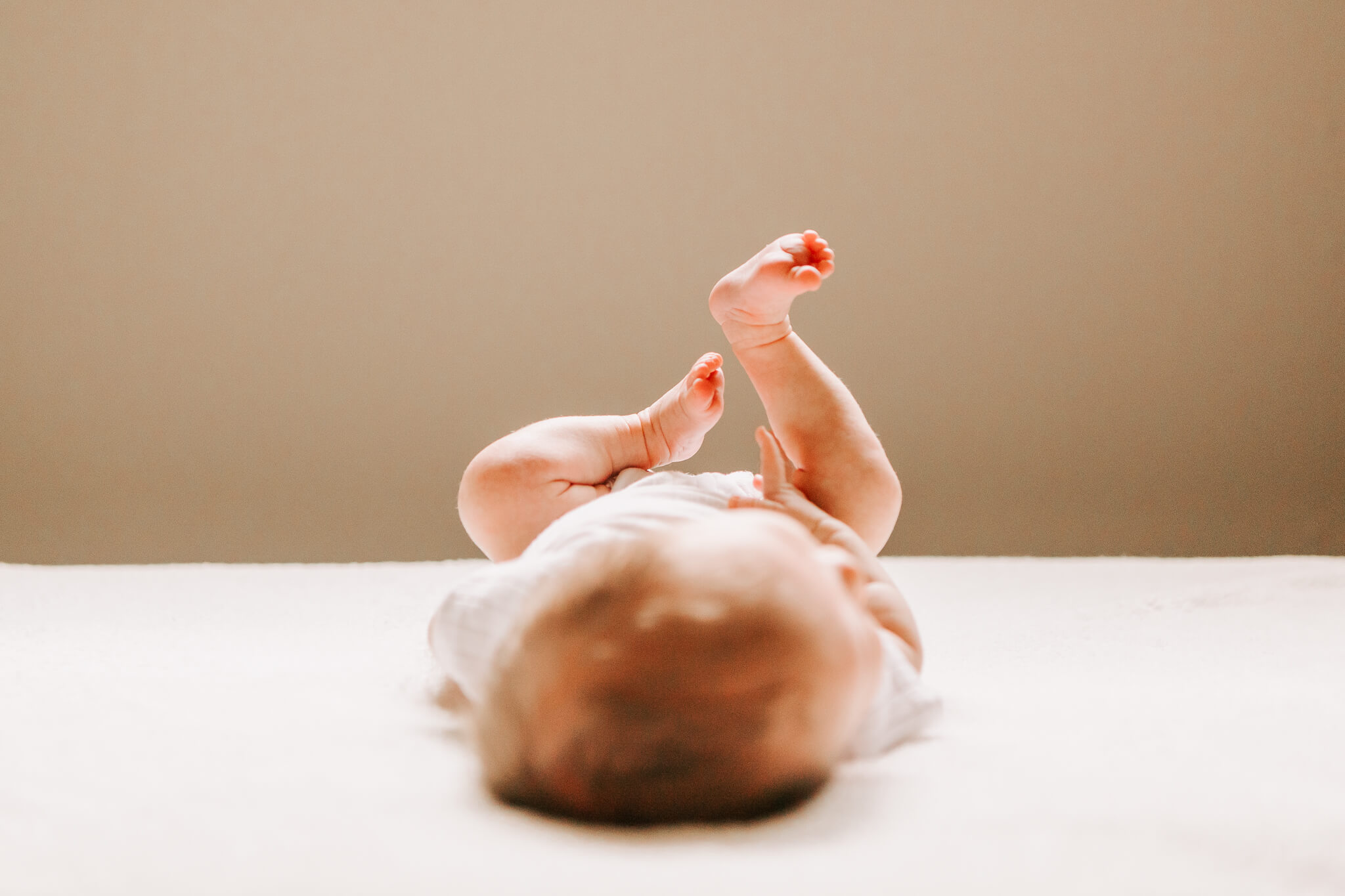 A newborn baby lies with its feet in the air