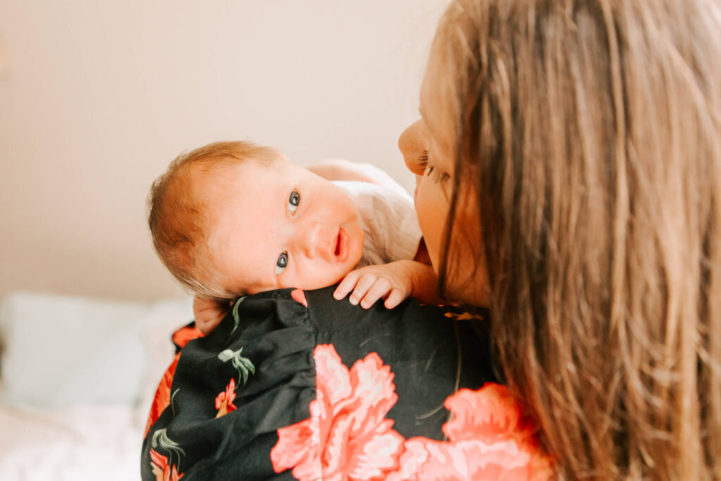 A mother holds her newborn baby on her shoulder