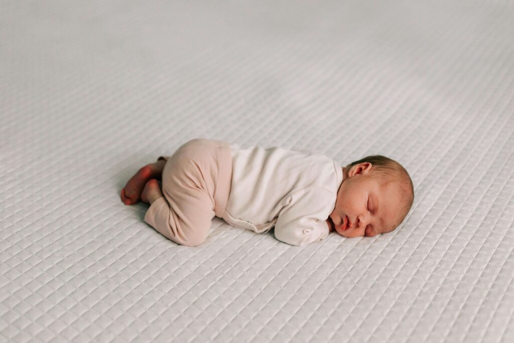 Newborn girl lays on white blanket during a newborn session with Jen White Photography Albany Oregon