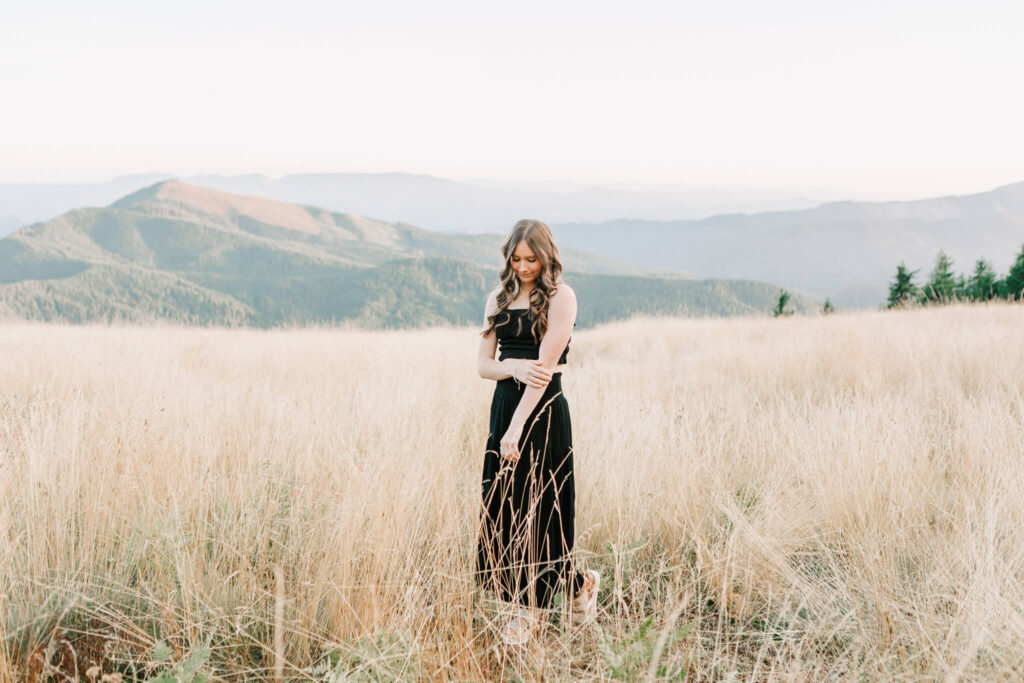 A high school senior poses in a field for senior portraits at Mary's Peak with Jen White Photography