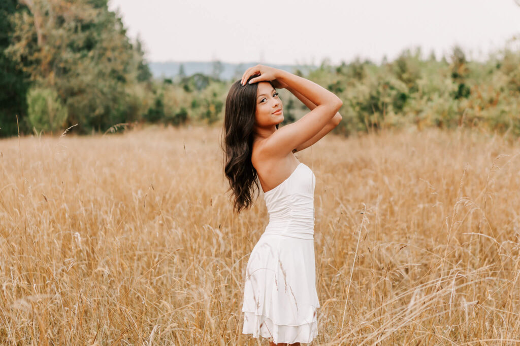 Senior portrait Albany, Oregon. Teen girl stands in white dress posing with hands above her head. Photo by Jen White Photography Albany, Oregon