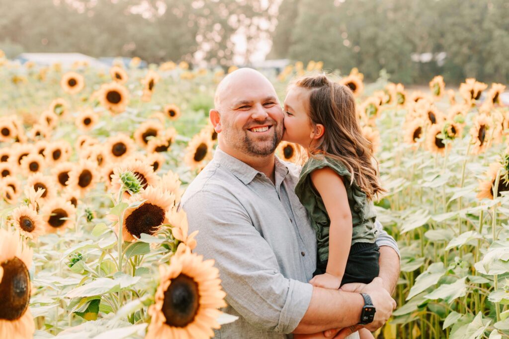 A father holds his young daughter in sunflower field – summer photo session in Albany, Oregon