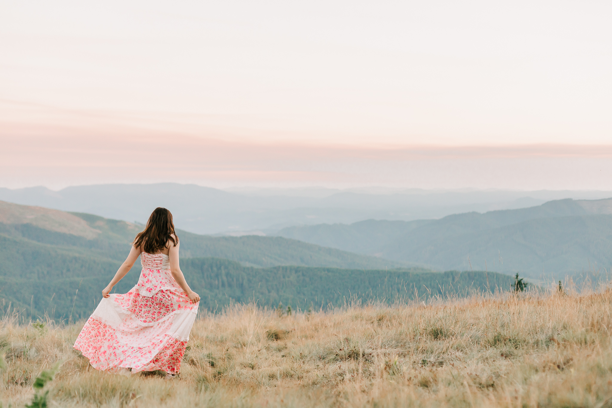 Oregon senior photos: teen in dress enjoying a scenic field with distant mountains behind her. Senior photo session with Jen White Photography of Albany Oregon