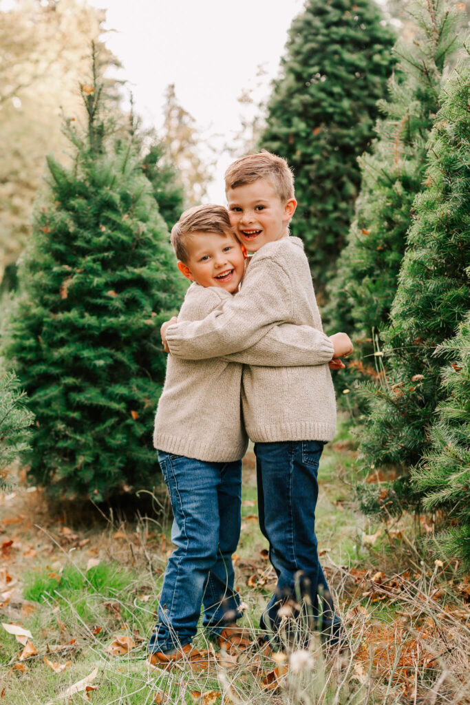 2 young boys hug each other at a Salem Christmas tree farm mini session event by Jen White Photography or Albany, Oregon