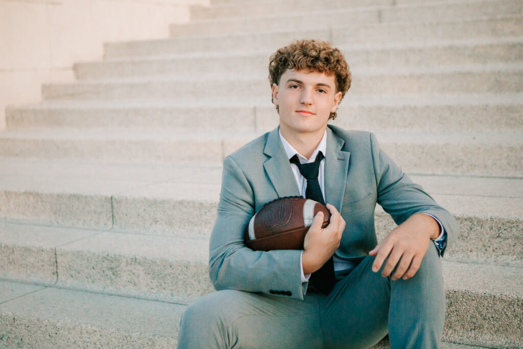 A senior boy sits on steps in Albany, Oregon posing for senior portraits with Jen White Photography