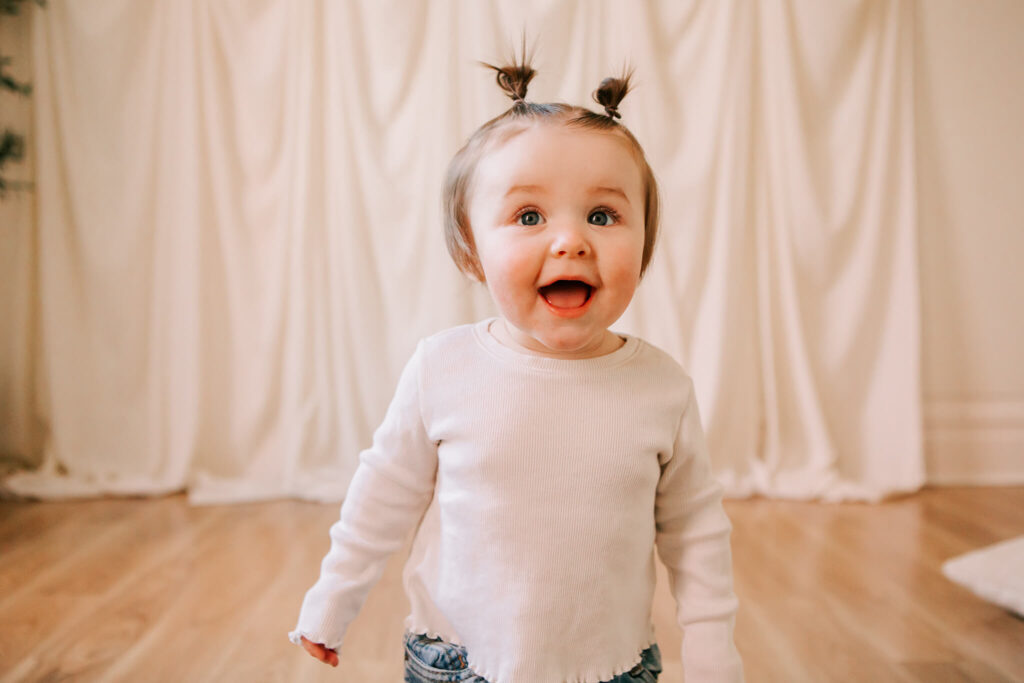 Toddler girl in pigtails smiles at the camera