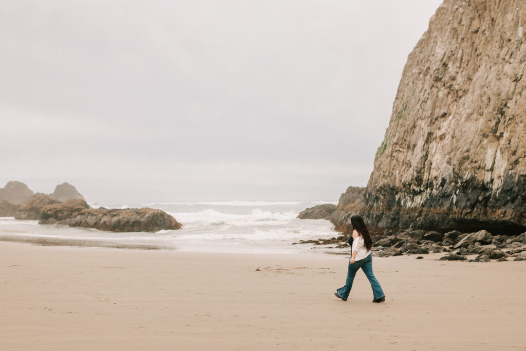 A young woman walks on the beach at Seal Rock Oregon