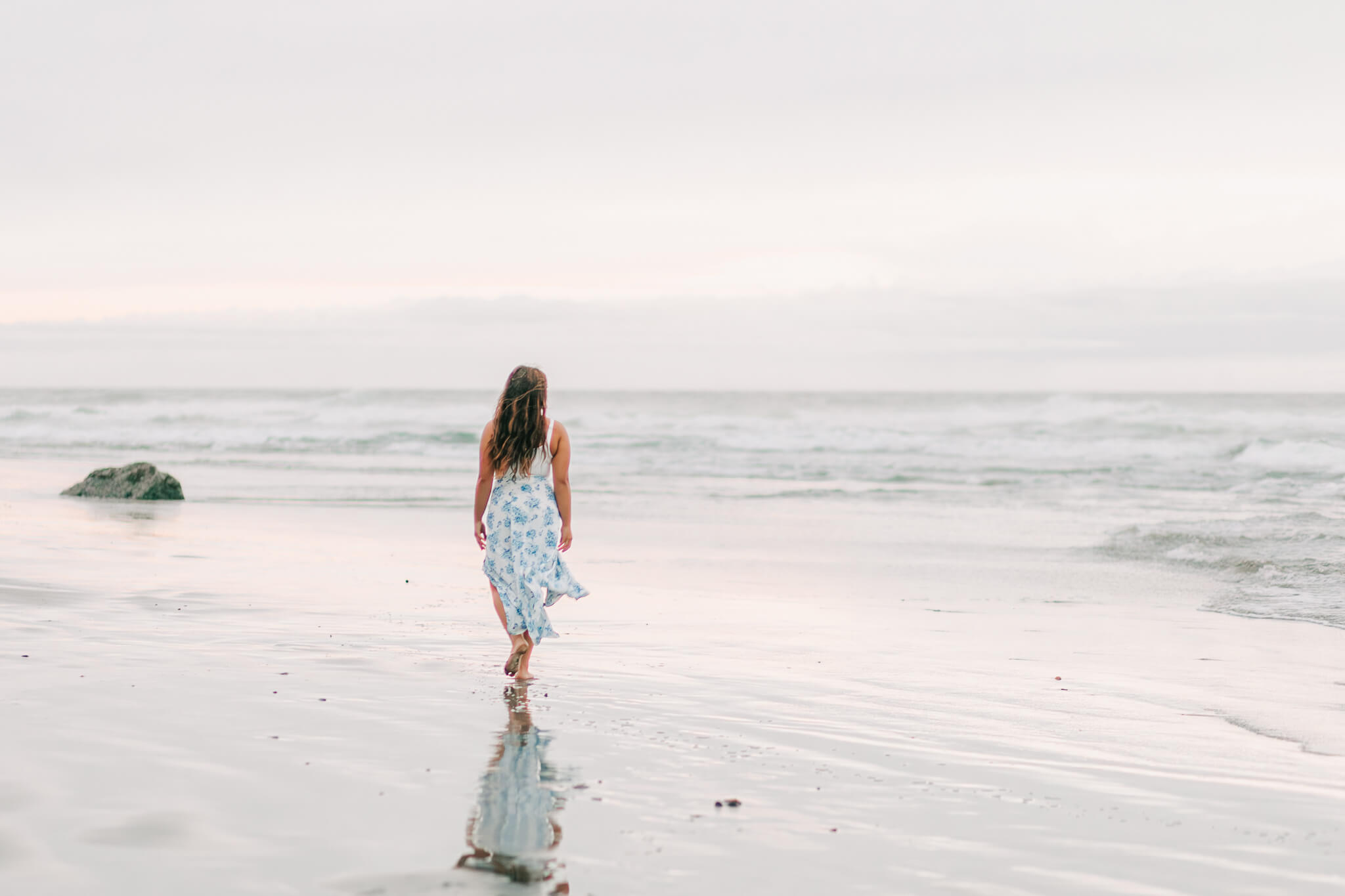 A young woman walks at Coquille Point on the beach