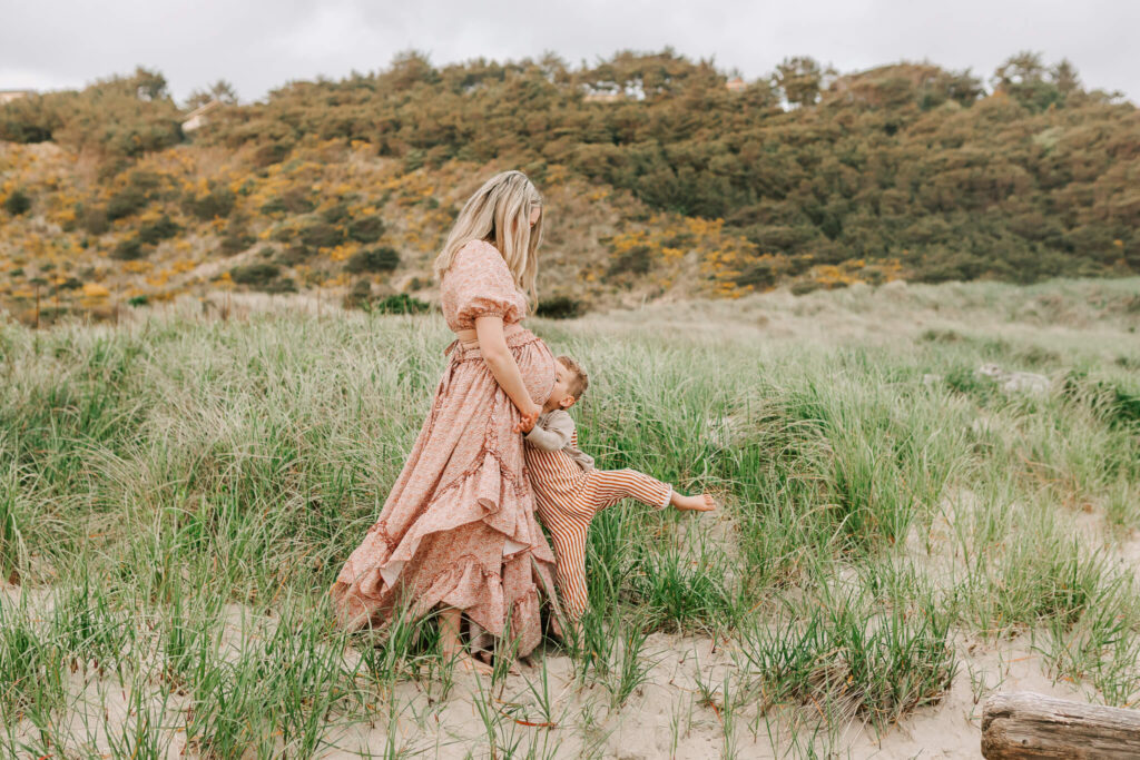 A small boy hugs his mom in the beach grass at Cape Kiwanda State Park in Oregon