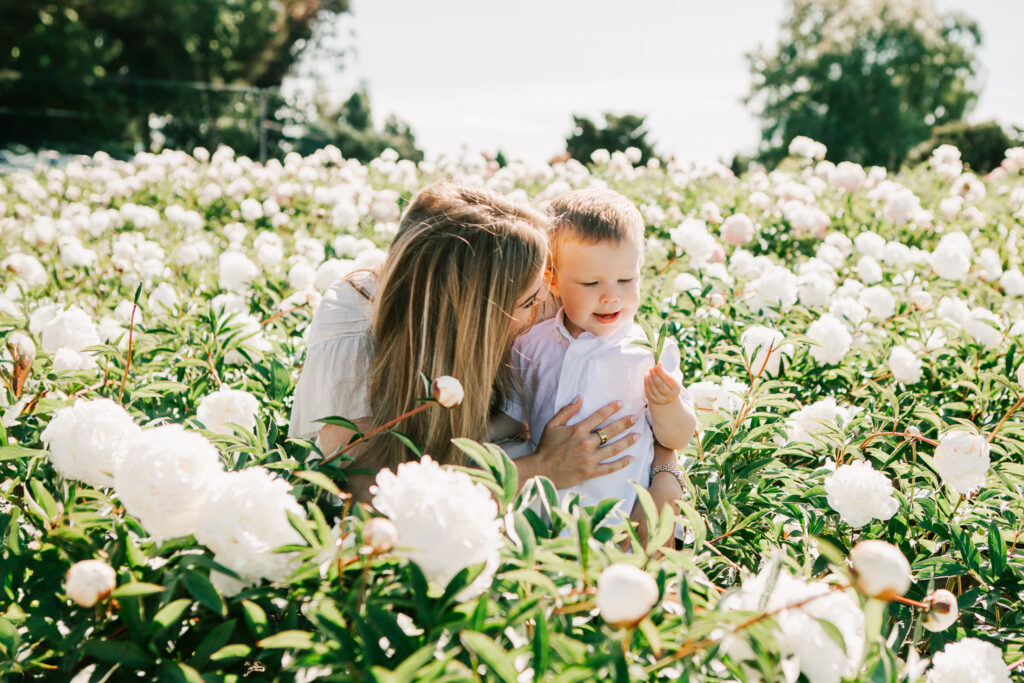 A mother plays with her toddler boy at Adleman Peony Gardens at a Spring Mini Family Photo Session with Jen White Photography