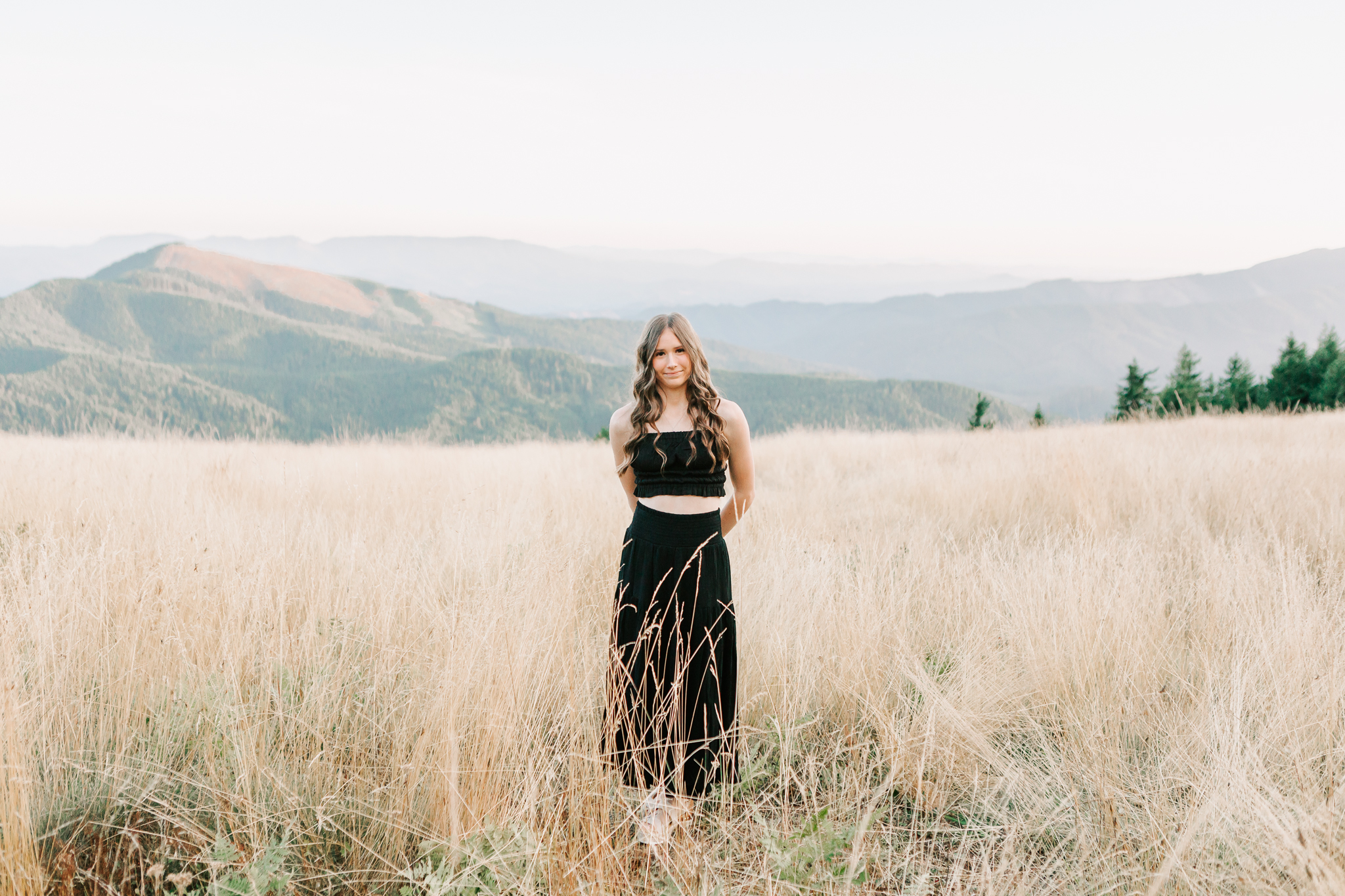 High school senior in a golden field with mountain views at a photography session in Oregon