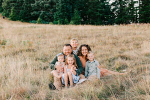 Parents and their small children sit on a blanket in a field
