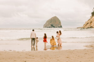 A family stands in the water playing at Cape Kiwanda Oregon