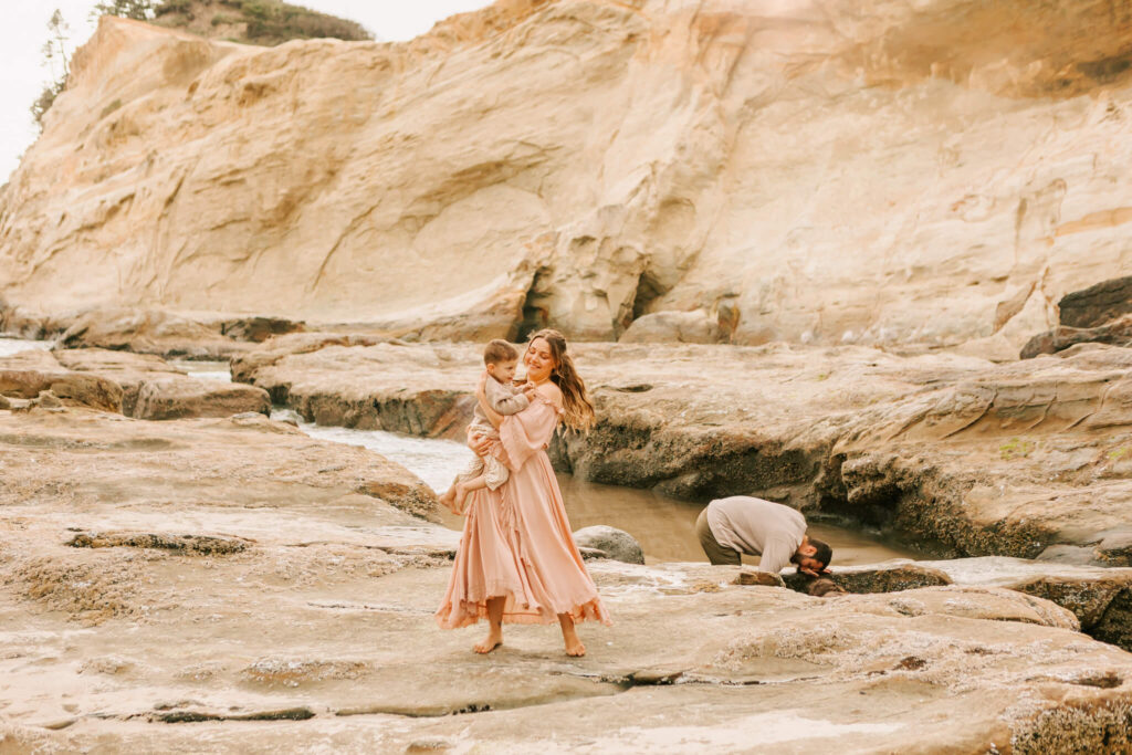 Mother walks holding son on beach at Cape Kiwanda, OR