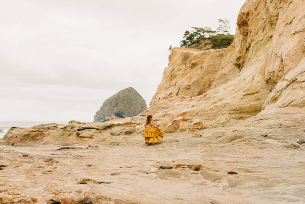 A young girl runs on the beach at Cape Kiwanda, OR