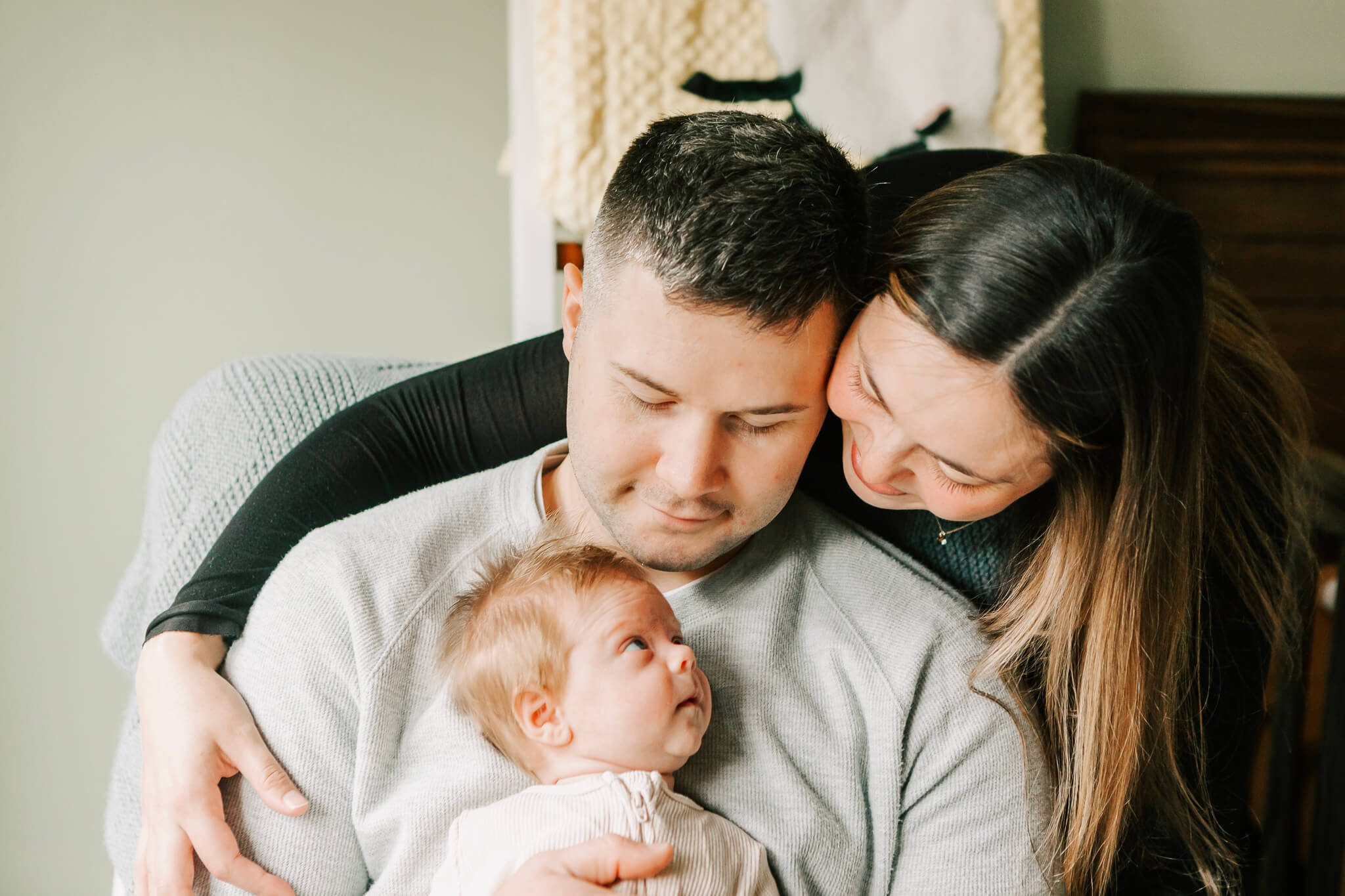 Mom, Dad, and Newborn baby snuggle during a newborn photoshoot with Jen White Photography