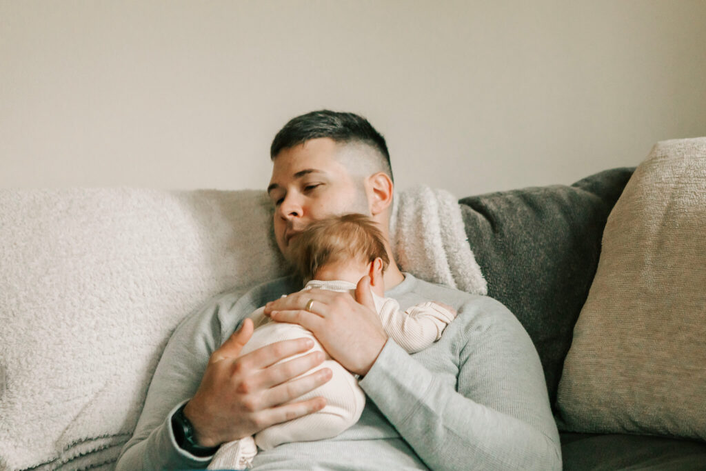 Dad relaxes with baby during lifestyle newborn photo session with Jen White Photography